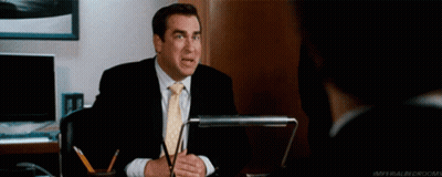Man In Suit Sitting At Desk With Pow Behind Him GIF