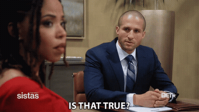 Man In Suit Sitting At Desk With Woman Behind Him Saying Is That True GIF