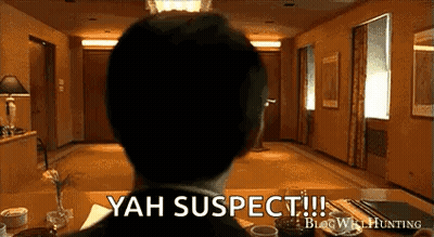 Man In Suit Sitting At Table Saying Yah Suspect GIF