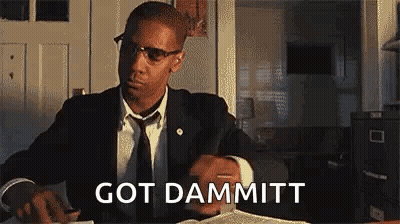 Man In Suit Sitting At Table With Book And Glasses GIF