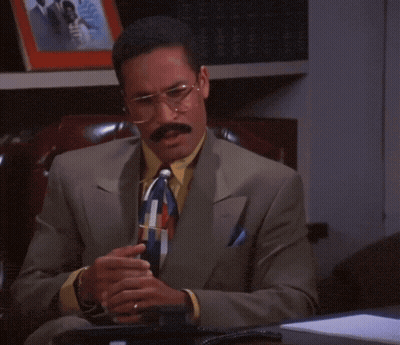 Man In Suit Sitting Before Bookshelf With Wedding Photo GIF