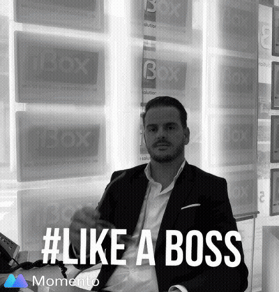 Man In Suit Sitting Before Ibox Signs GIF
