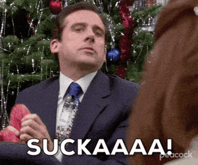 Man In Suit Sitting By Christmas Tree Saying Suckaaa GIF