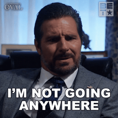 Man In Suit Sitting In Chair Saying I'm Not Going Anywhere GIF