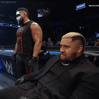 Man In Suit Sitting In Front Of Bestofguerraillas Sign GIF