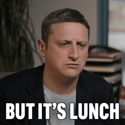 Man In Suit Sitting In Front Of But Its Lunch Sign GIF