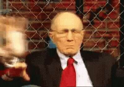 Man In Suit Sitting In Front Of Chain Link Fence GIF