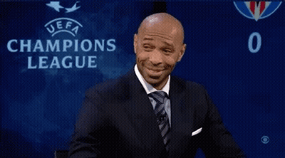 Man In Suit Sitting In Front Of Champions League Sign GIF
