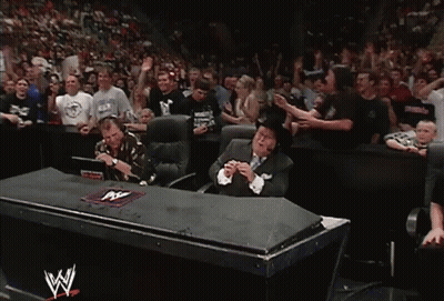 Man In Suit Sitting In Front Of Crowd With W Logo GIF