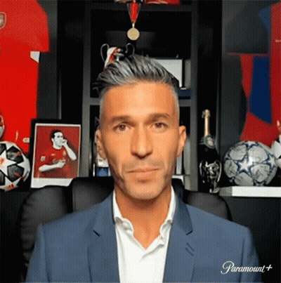 Man In Suit Sitting In Front Of Paramount Plus Sign GIF