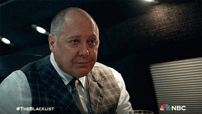 Man In Suit Sitting In Front Of The Blacklist Sign GIF