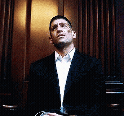 Man In Suit Sitting In Front Of Wooden Wall GIF