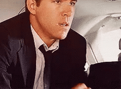 Man In Suit Sitting In Plane Back Seat GIF