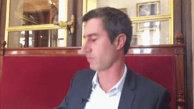 Man In Suit Sitting In Red Cushion Chair GIF