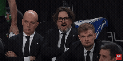Man In Suit Sitting In Stadium With Arms Up And Subscribe Button GIF