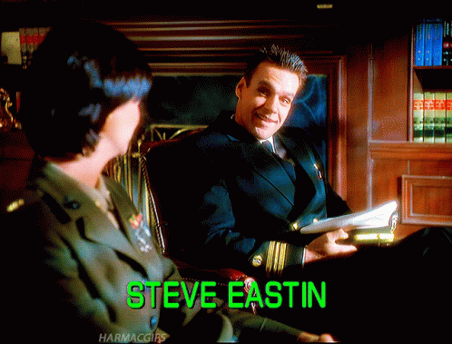 Man In Suit Sitting Next To Woman With Steve Eastin Displayed GIF