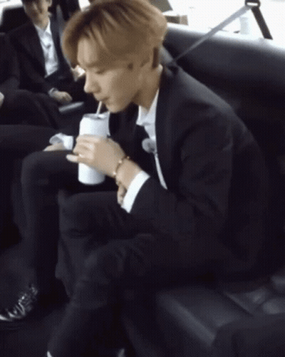 Man In Suit Sitting On Couch Holding Soda GIF
