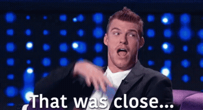 Man In Suit Sitting On Couch Saying That Was Close GIF