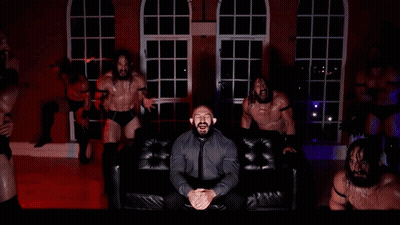 Man In Suit Sitting On Couch Surrounded By Men GIF