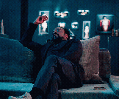 Man In Suit Sitting On Couch With Arms Outstretched GIF
