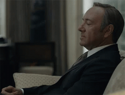 Man In Suit Sitting On Couch With Eyes Closed And Hands Folded GIF