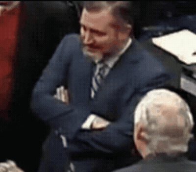 Man In Suit Sitting With Arms Crossed In Crowd GIF