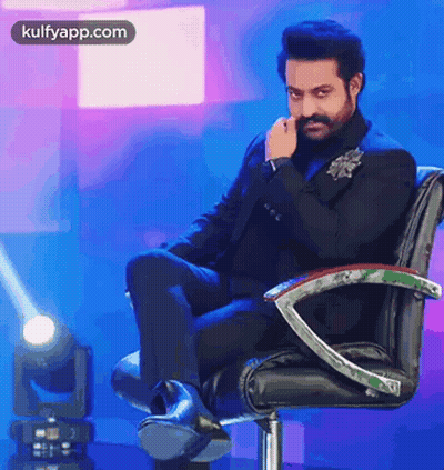 Man In Suit Sitting With Hand On Face GIF