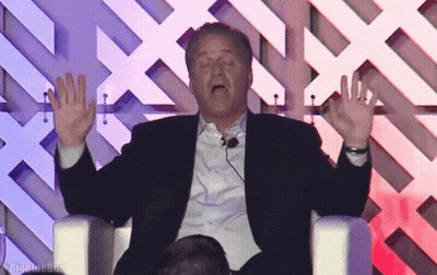 Man In Suit Sitting With Hands Up Saying Big GIF