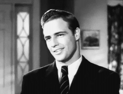 Man In Suit Smiling At Camera In Black And White GIF