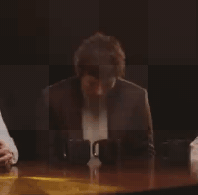 Man In Suit Smiling At Table With Two Mugs GIF