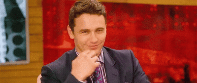 Man In Suit Smiling Before Red Wall GIF