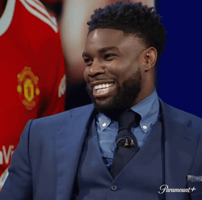 Man In Suit Smiling Beside Manchester United Shirt GIF