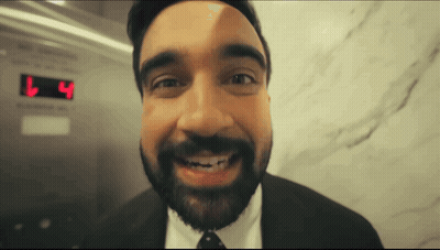 Man In Suit Smiling In Front Of L4 Display GIF