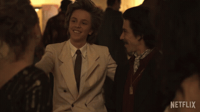 Man In Suit Smiling In Front Of Netflix Sign GIF