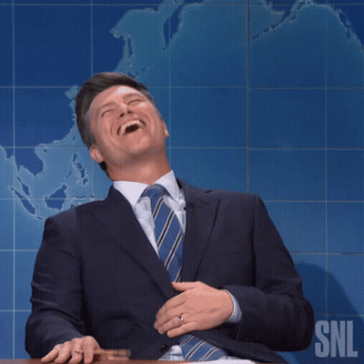 Man In Suit Smiling In Front Of SNL Logo GIF