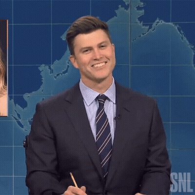 Man In Suit Smiling In Front Of SNL Sign GIF