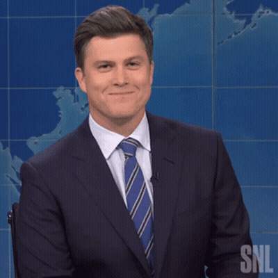 Man In Suit Smiling In Front Of SNL Sign GIF