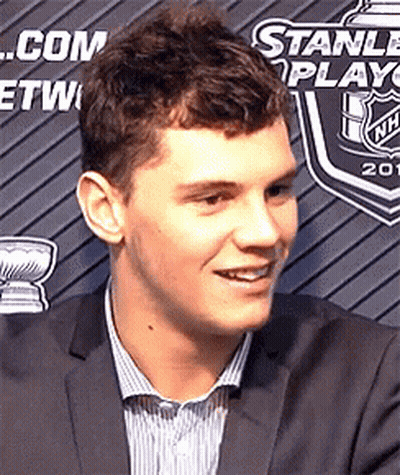 Man In Suit Smiling In Front Of Stanley Cup Banner GIF