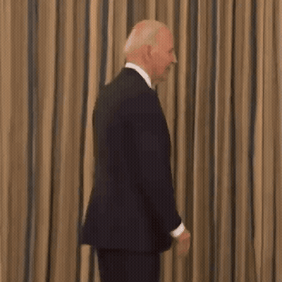 Man In Suit Smiling In Front Of Striped Curtain GIF