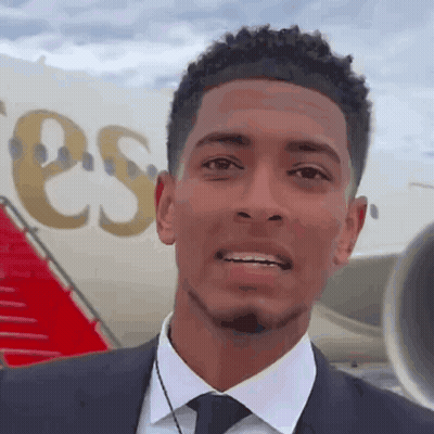 Man In Suit Smiling Next To Plane Saying ESS GIF