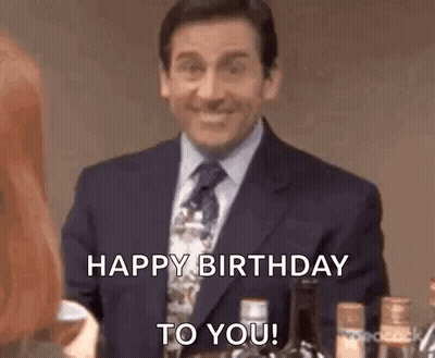 Man In Suit Smiling Saying Happy Birthday To You Next To Woman GIF
