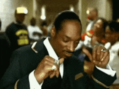 Man In Suit Smoking Cigarette In Crowded Room GIF