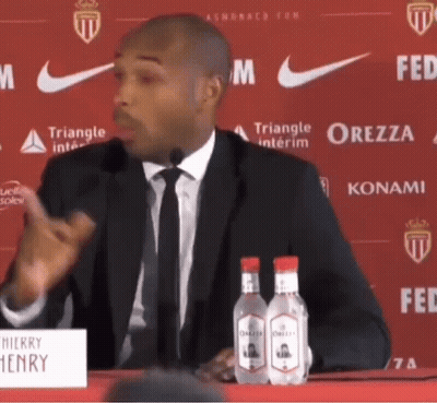 Man In Suit Speaking Into Microphone At Henry Sign GIF