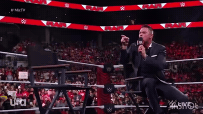 Man In Suit Speaking Into Microphone At Wrestling Match GIF