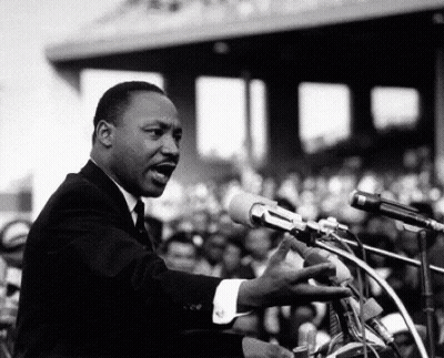 Man In Suit Speaking Into Microphone Before Crowd GIF