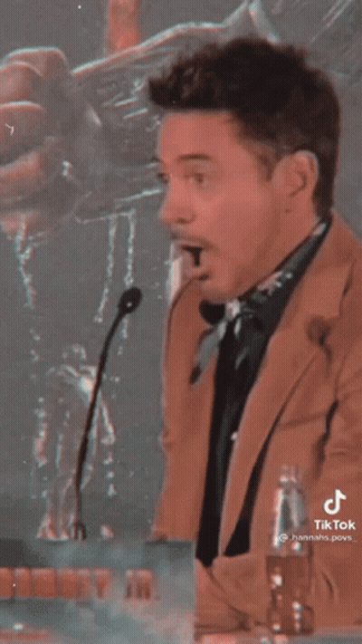 Man In Suit Standing At Microphone With Mouth Open GIF