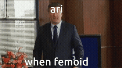 Man In Suit Standing At Window Saying Ari When Femoid GIF