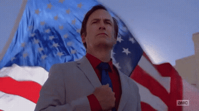 Man In Suit Standing Before American Flag GIF
