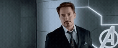 Man In Suit Standing Before Avengers Logo GIF