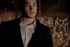 Man In Suit Standing Before Christmas Tree GIF
